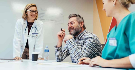 Two health care workers and a business person discuss healthcare entities in a conference room