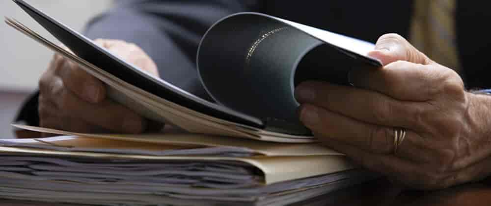 Close up on the hands of a man looking through probate paperwork