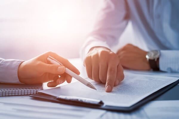 Close-up of the hands of two businessmen reviewing a contract.